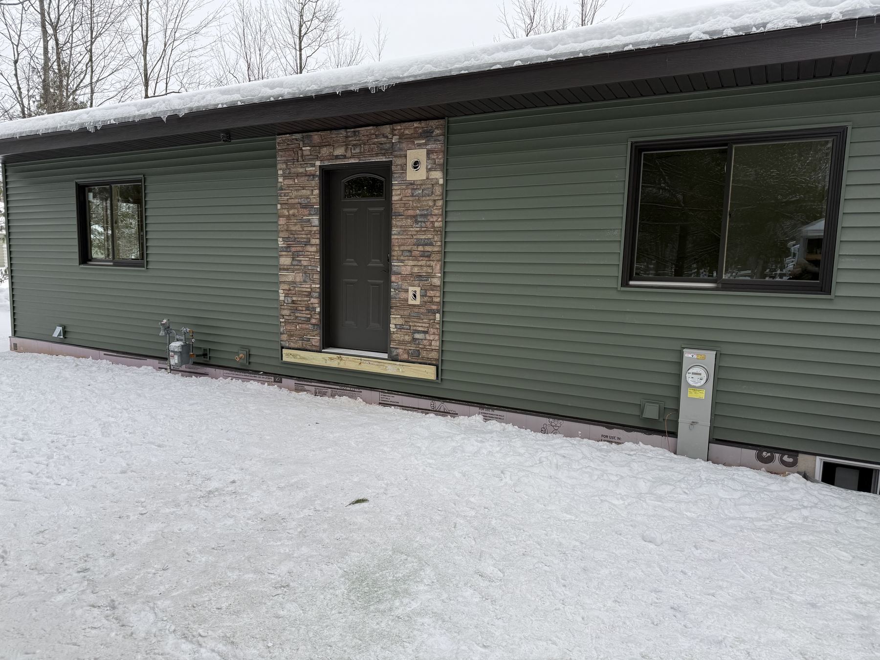 Front entry with stone accent and stained glass door, winter